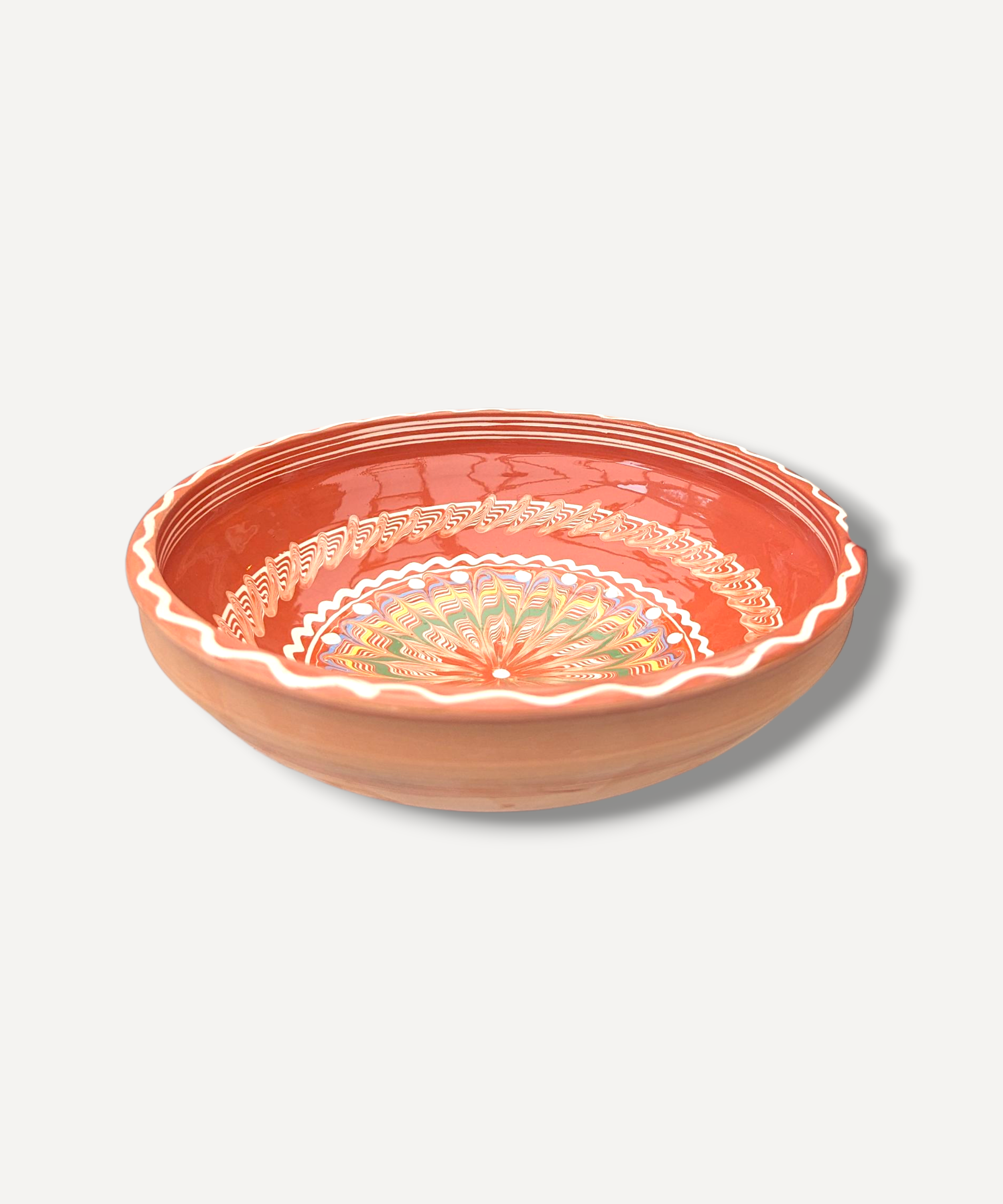 Handcrafted earthenware bowl with floral patterns on a light gray background