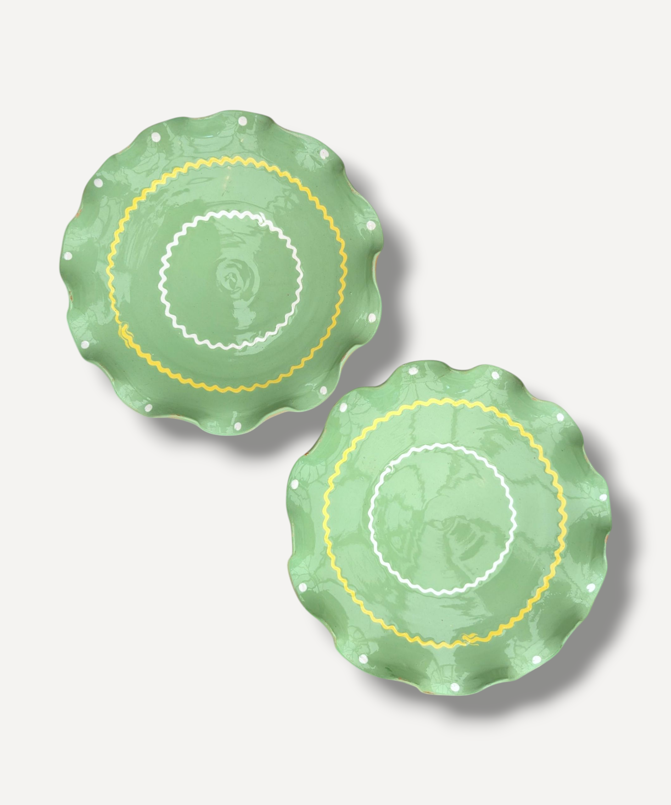 Two green ceramic plates with decorative patterns on a light gray background