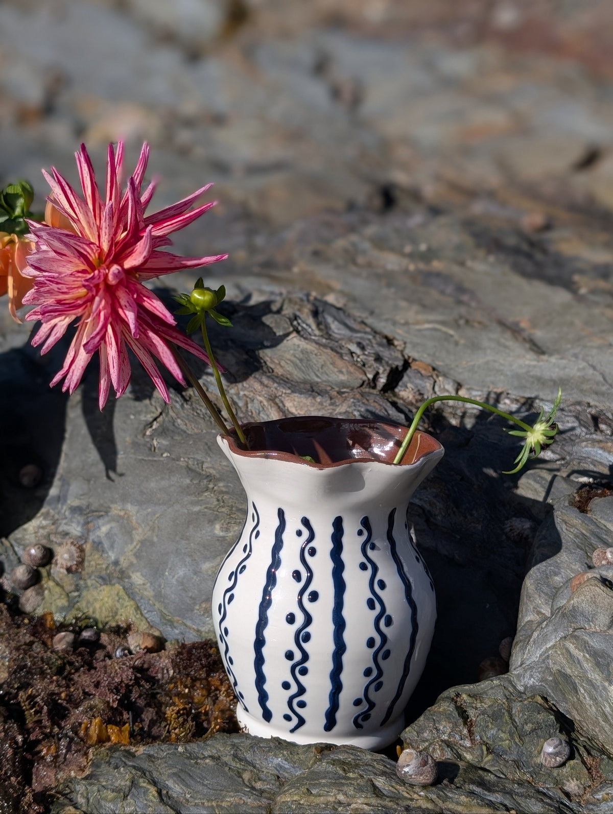 Handmade white Romanian earthenware vase with cobalt-blue wavy lines and dotted motifs and a brown interior.