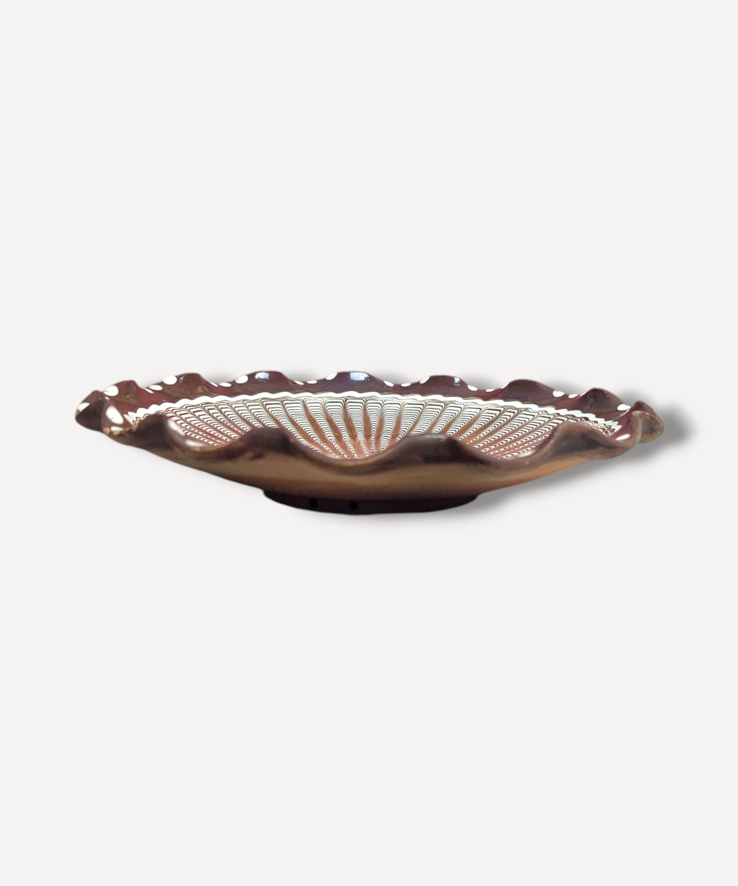 Decorative ceramic plate with scalloped edge on a white background