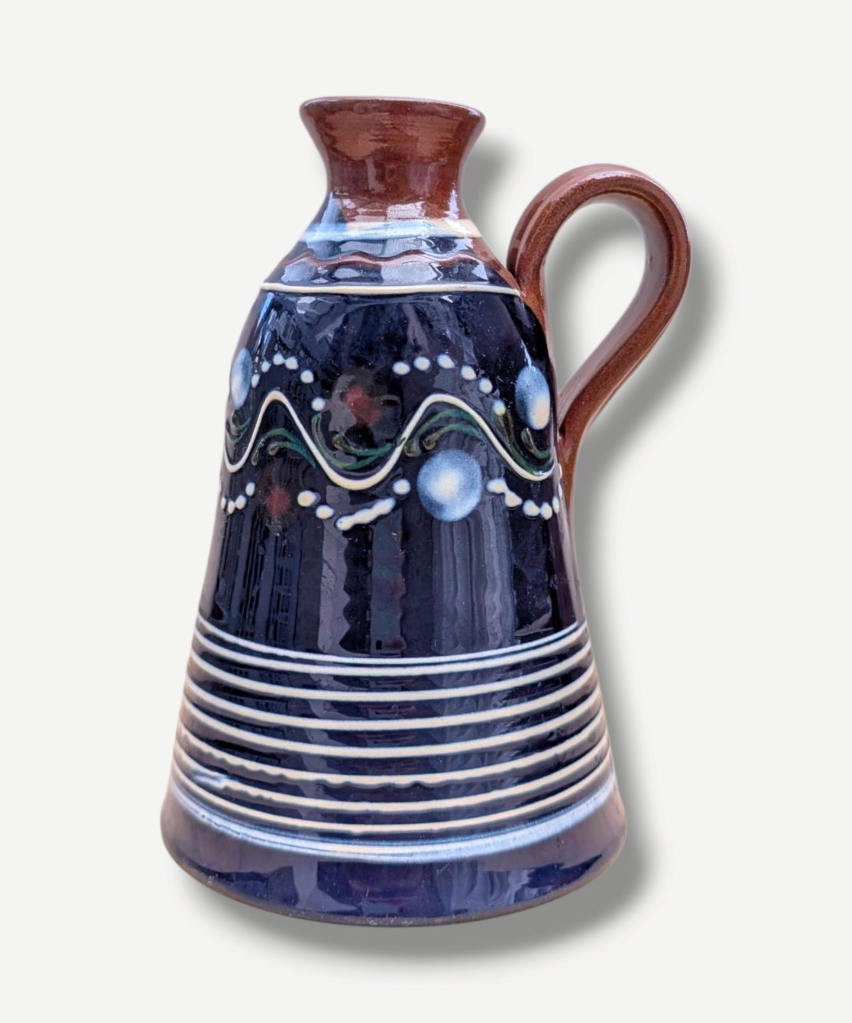 Handmade cobalt-blue Romanian earthenware jug with white, blue, green and red folk motifs and a chocolate-brown handle.