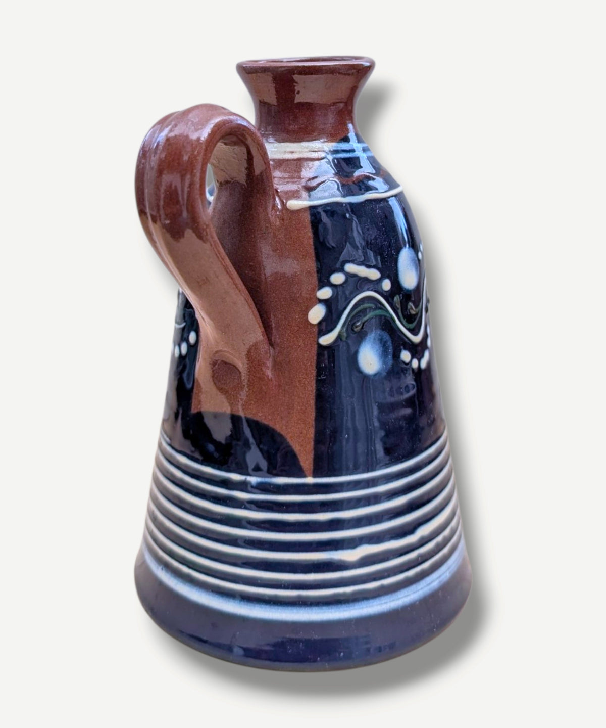 Handmade cobalt-blue Romanian earthenware jug with white, blue, green and red folk motifs and a chocolate-brown handle.