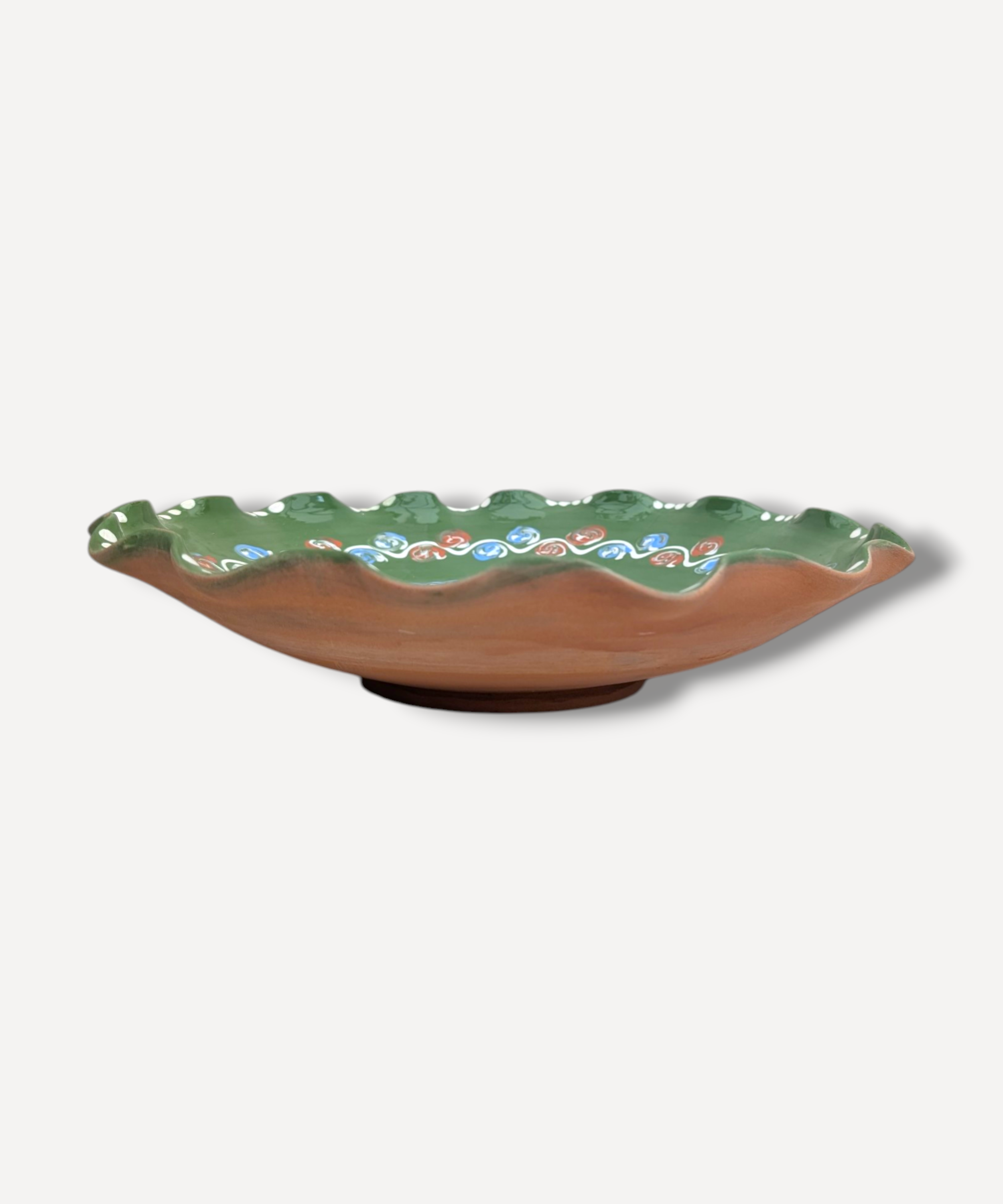 Ceramic plate with green rim and floral patterns on a white background