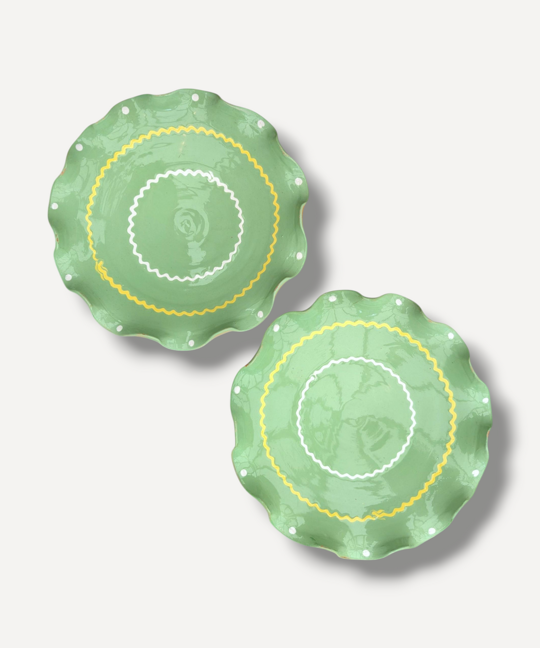 Two green ceramic plates with decorative patterns on a light gray background
