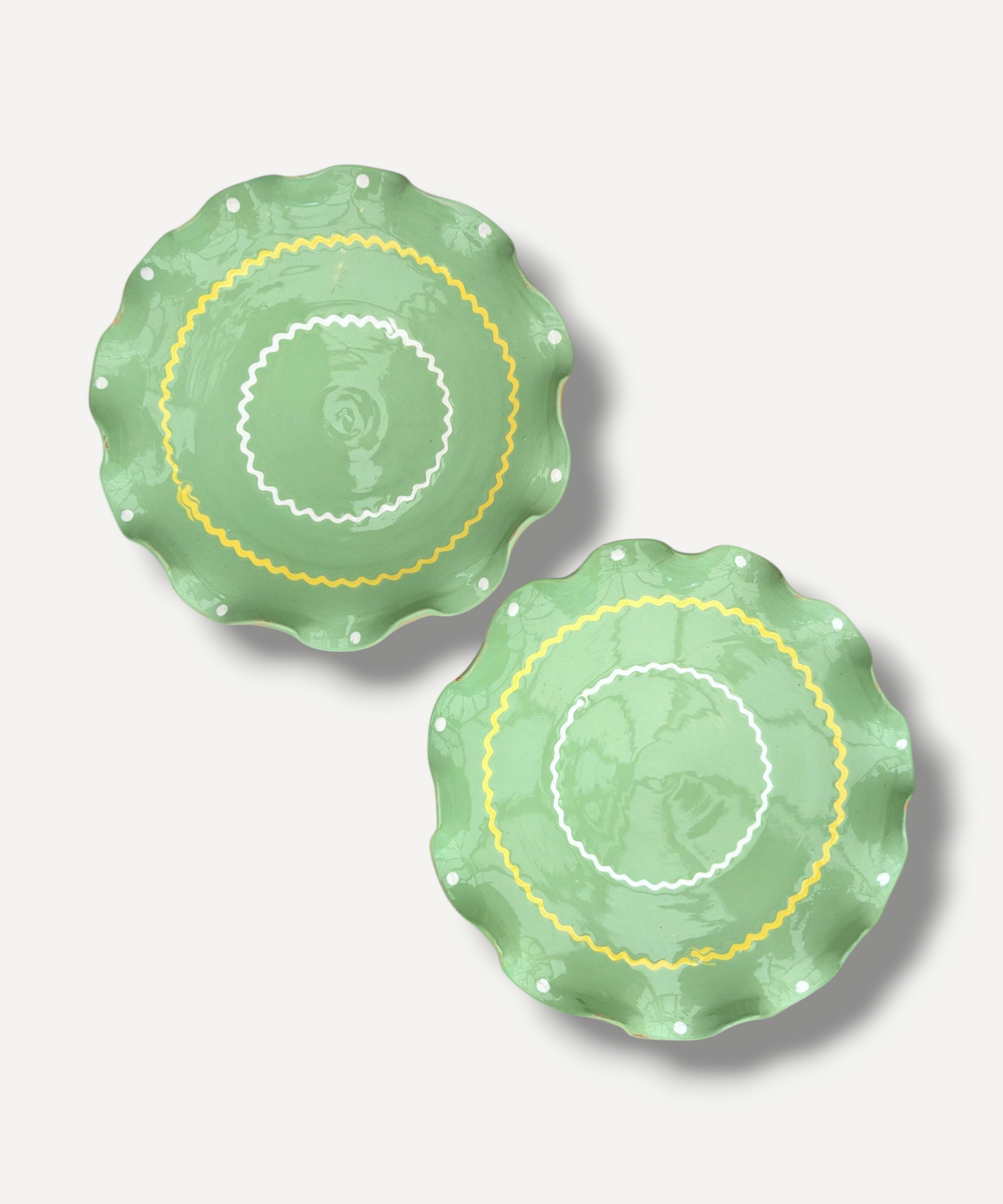 Two green ceramic plates with decorative patterns on a light gray background