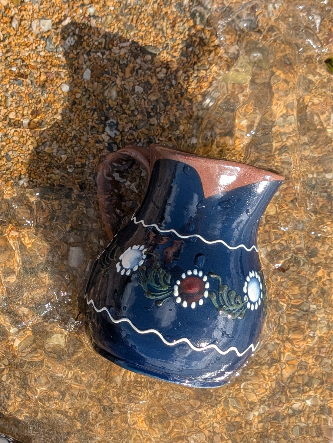 Handmade cobalt-blue Romanian earthenware jug with white floral and dotted motifs, a chocolate-brown rim and rounded body.