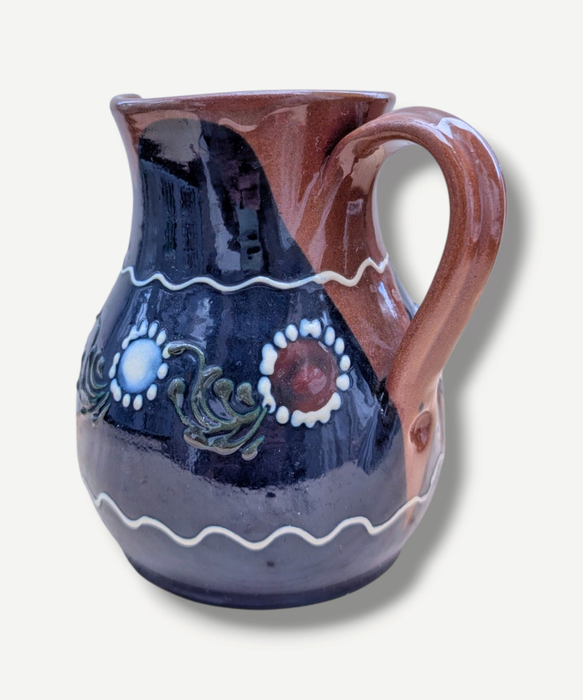 Handmade cobalt-blue Romanian earthenware jug with white floral and dotted motifs, a chocolate-brown rim and rounded body.