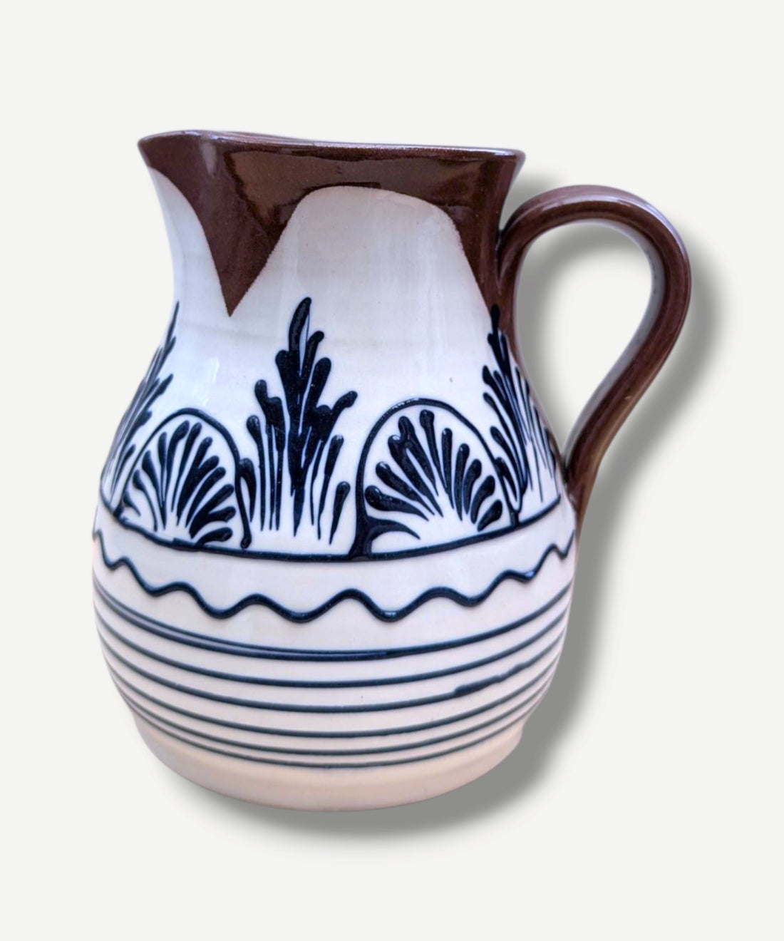Handmade white Romanian earthenware jug with black floral and botanical motifs, horizontal stripes and a chocolate-brown rim and handle