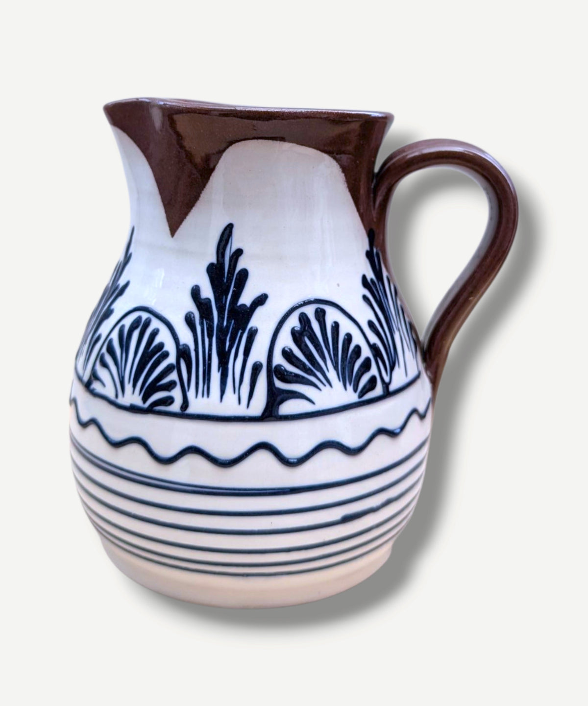 Handmade white Romanian earthenware jug with black floral and botanical motifs, horizontal stripes and a chocolate-brown rim and handle