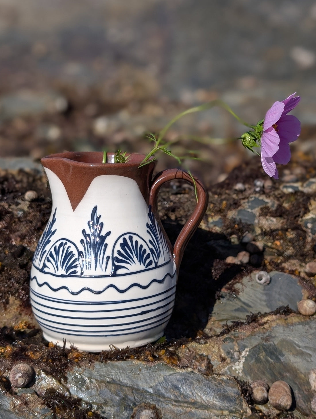 Handmade white Romanian earthenware jug with black floral and botanical motifs, horizontal stripes and a chocolate-brown rim and handle