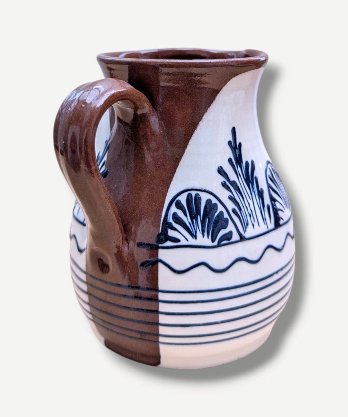 Handmade white Romanian earthenware jug with black floral and botanical motifs, horizontal stripes and a chocolate-brown rim and handle