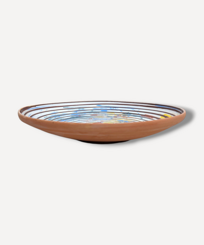 Hand decorated Romanian ceramic platter with spiral folk pattern in blue ochre and terracotta tones