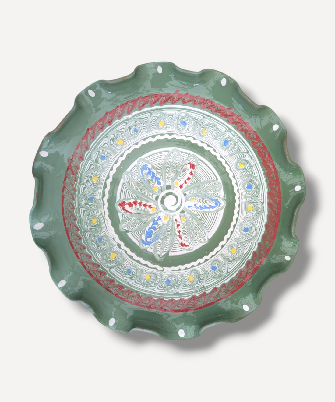 Decorative plate with a green rim and colorful center on a white background
