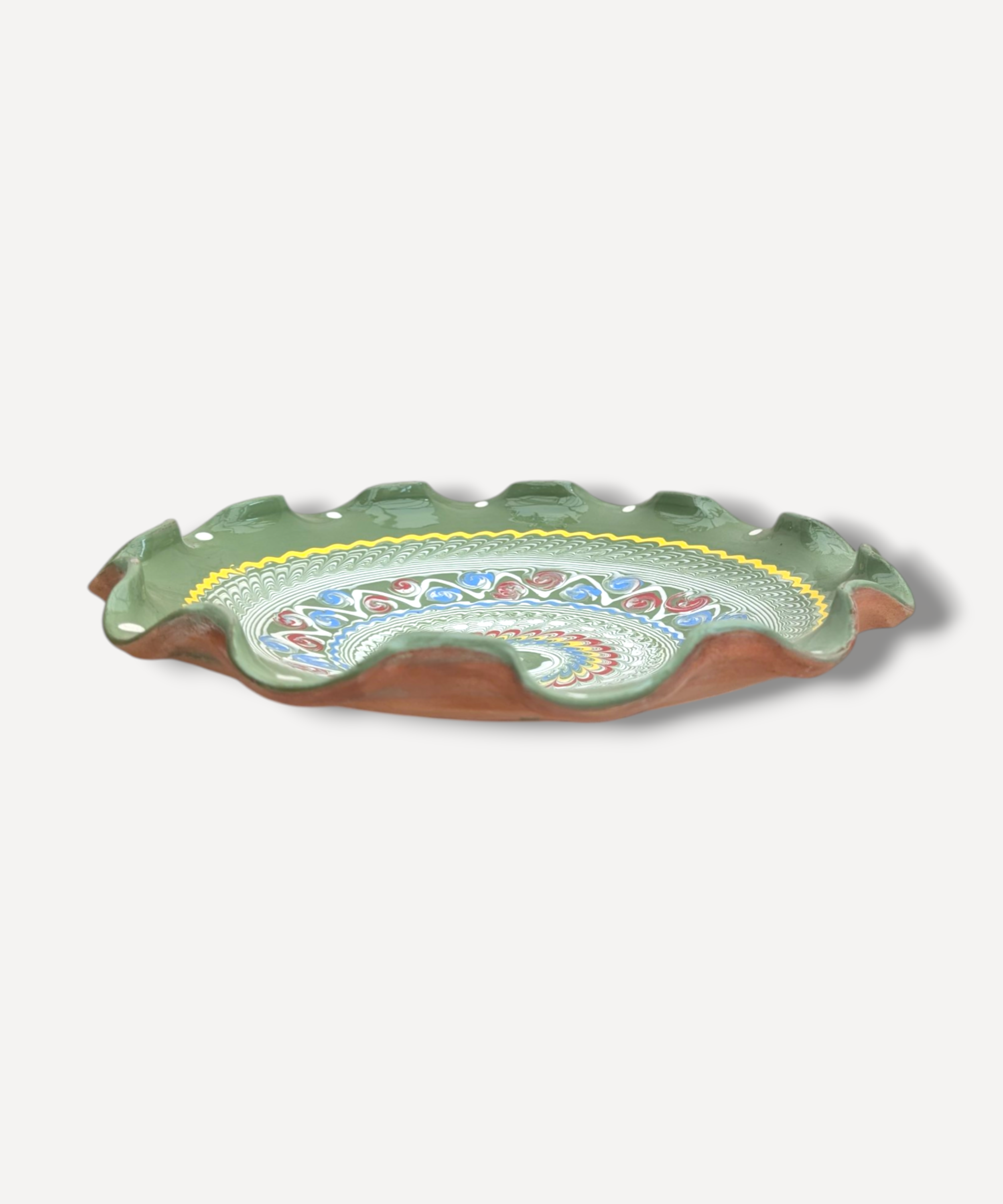 Decorative ceramic dish with a green rim and colorful interior on a white background