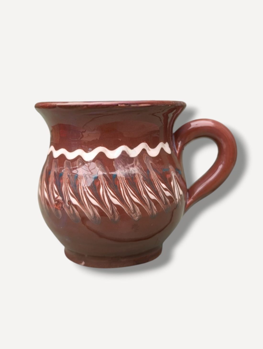 Handmade dark chocolate Romanian ceramic mug with traditional folk decoration on outdoor café table