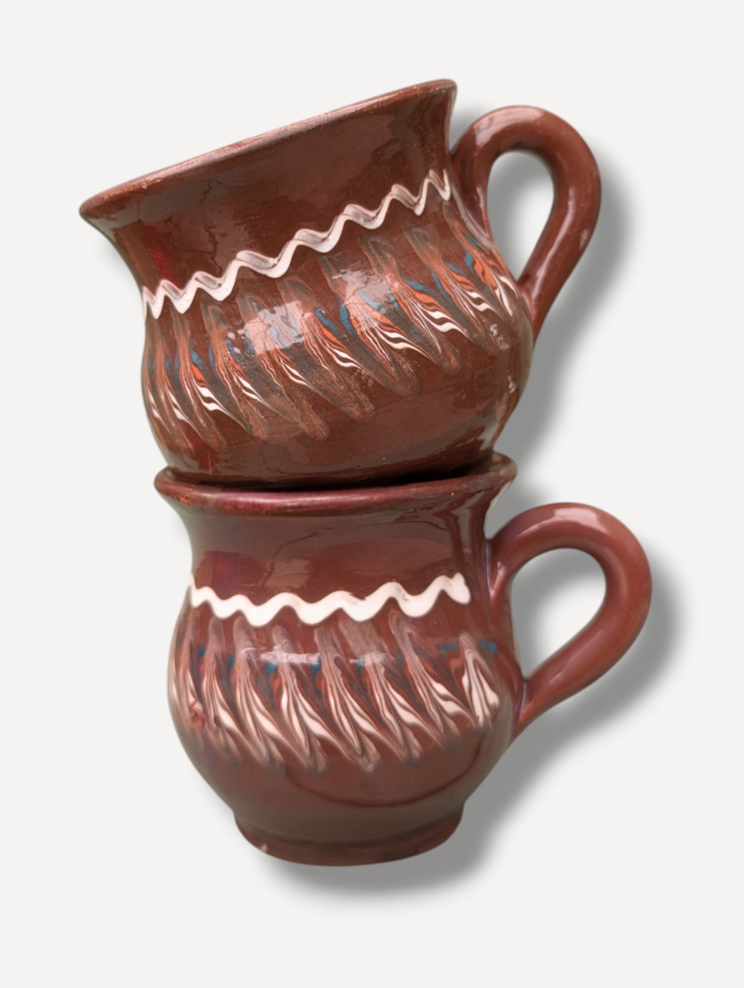 Handmade dark chocolate Romanian ceramic mug with traditional folk decoration on outdoor café table