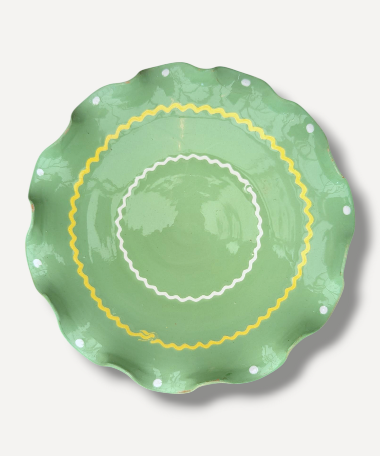 Green ceramic plate with yellow rim on a light gray background
