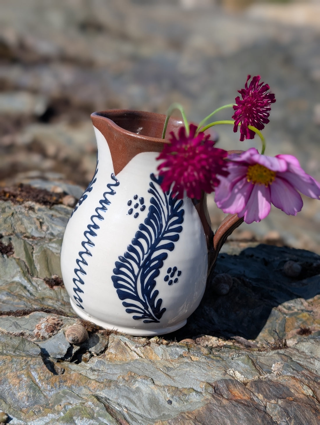 Handmade white Romanian earthenware vase with cobalt blue floral motifs, a rounded body and a sculptural narrow waist.By Casa De Folklore