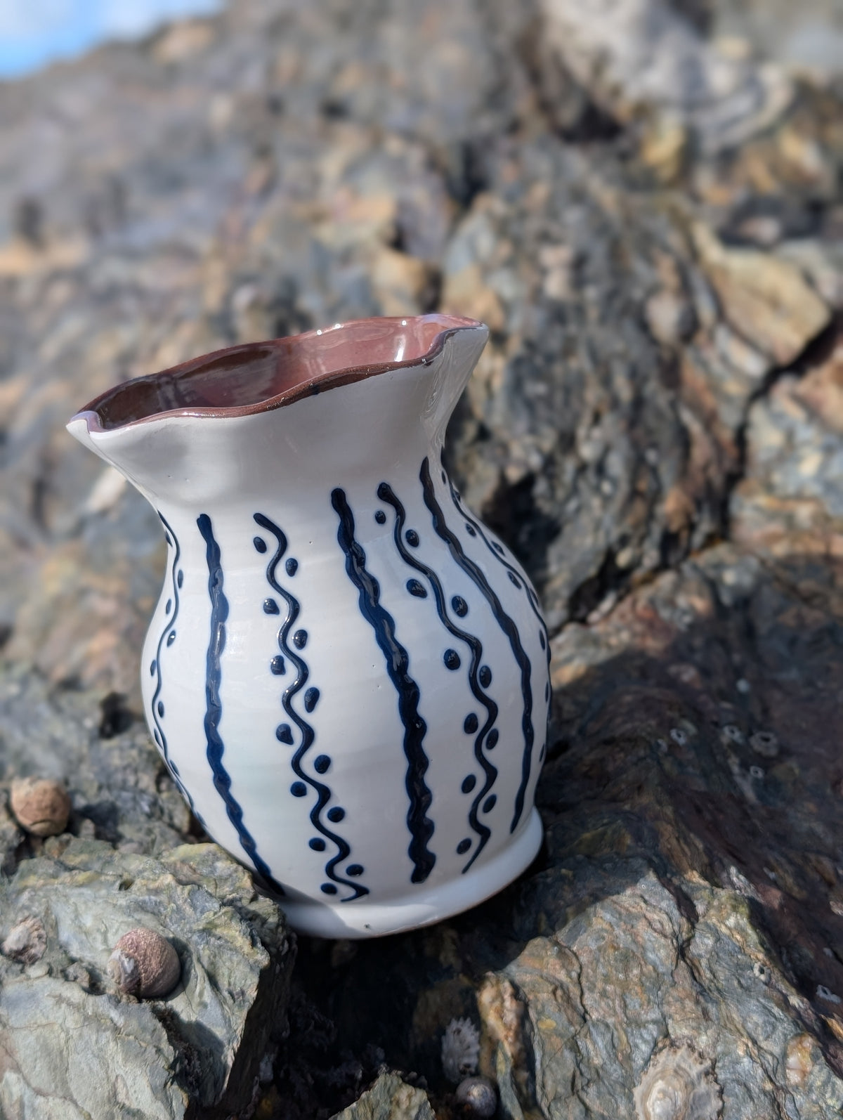 Handmade white Romanian earthenware vase with cobalt-blue wavy lines and dotted motifs and a brown interior.
